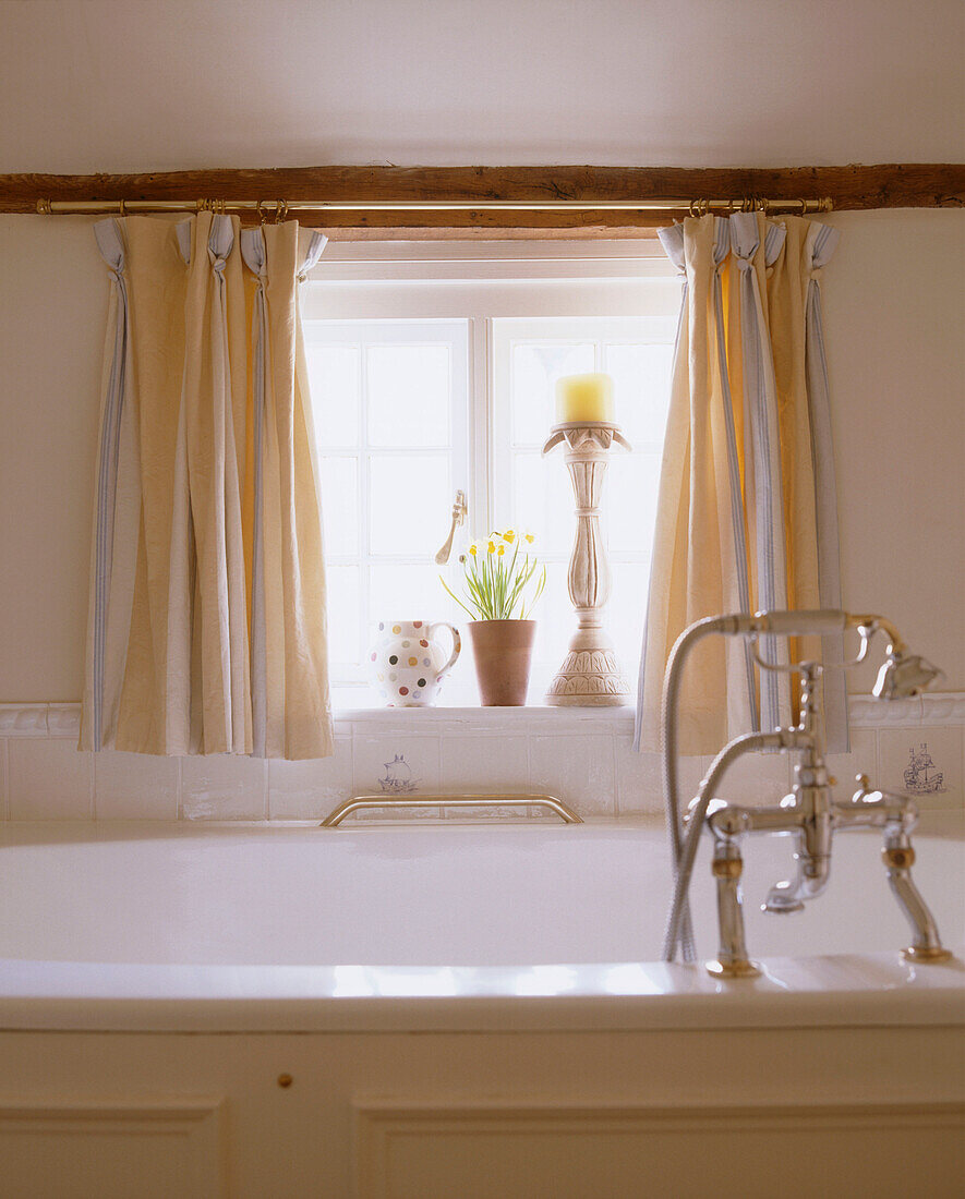 Detail of a traditional bathroom with large bathtub in front of a small window