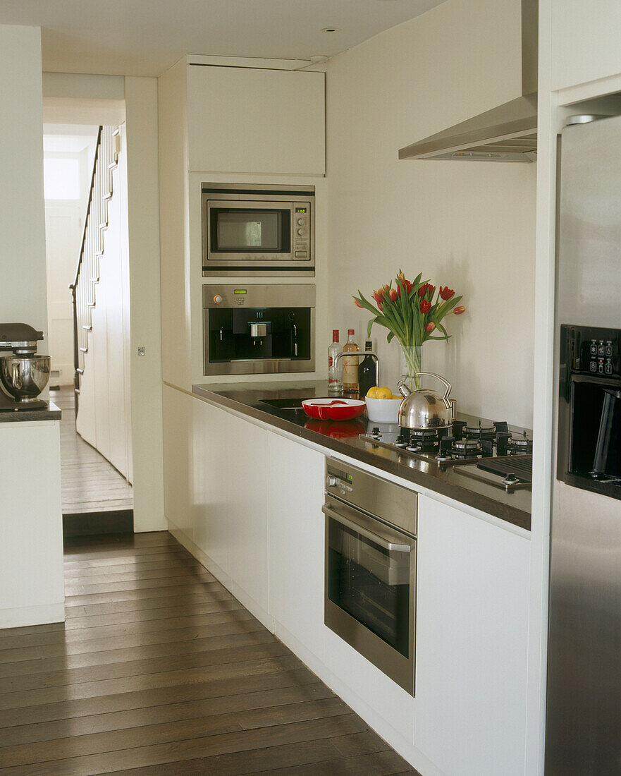 A modern kitchen with white units and inbuilt stainless steel appliances