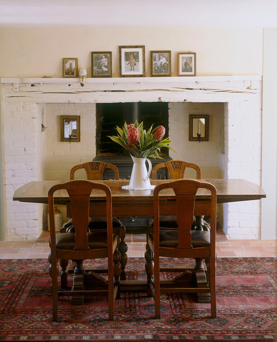 Rustikaler Esstisch aus Holz mit Blumenvase am Kamin in einem Zimmer im Landhausstil