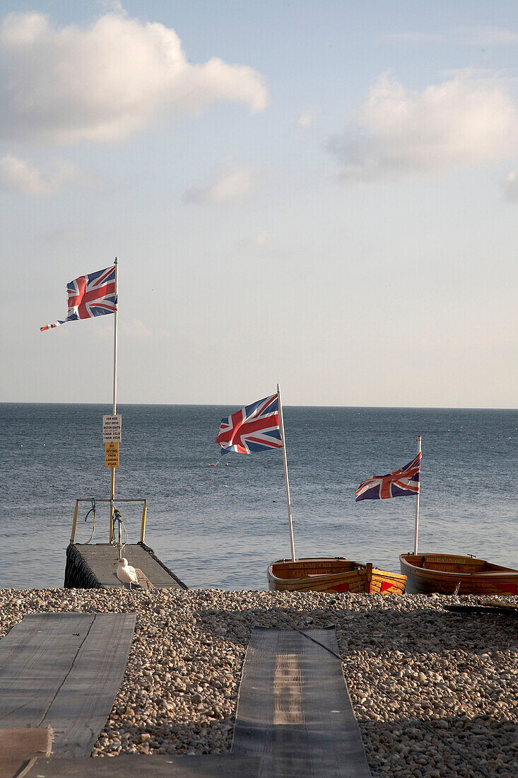 Union Jacks im Wind und Ruderboote am Strand von Devon