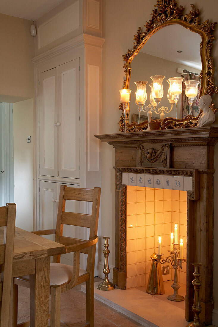 Wooden chair at fireplace with lit candles and decorative gilt mirror in Arundel, West Sussex