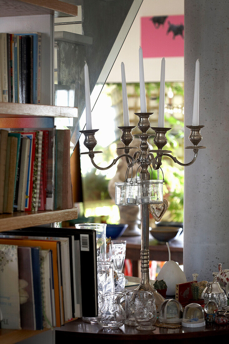 Silberner Kerzenständer mit Glasornamenten und Bücherregal