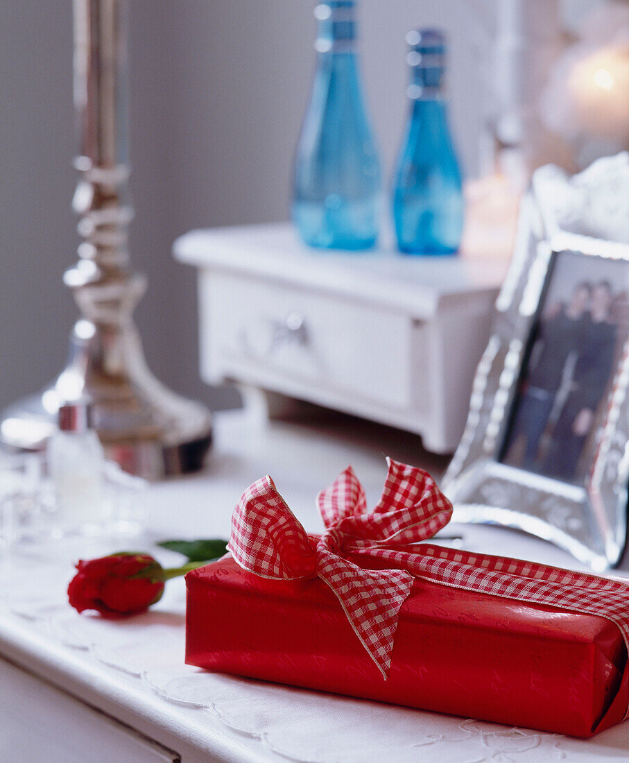 Wrapped gift with gingham ribbon on a white painted dressing table