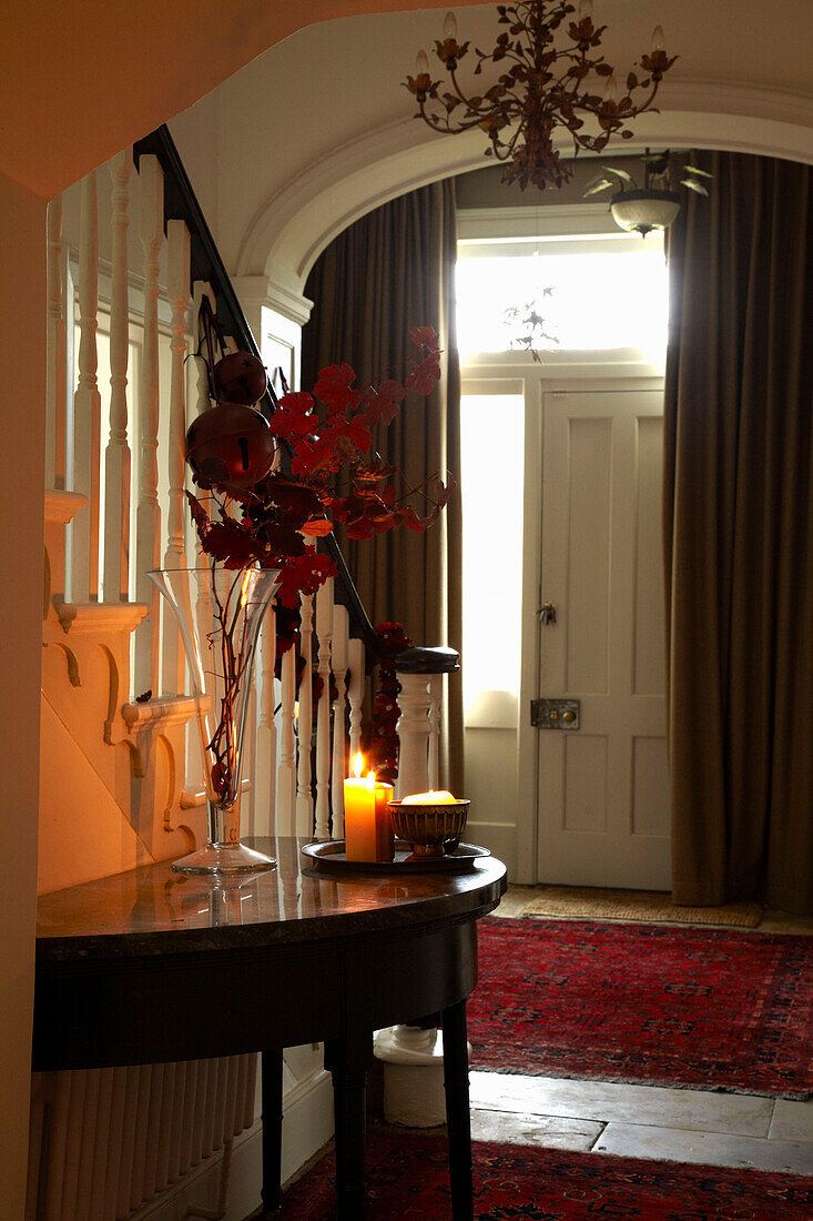 Lit candle on demilune table with curtained entrance doorway