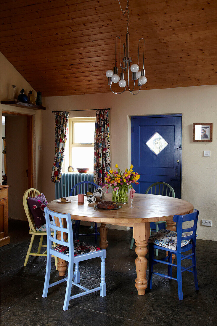 Light fitting above wooden table with mismatched chairs