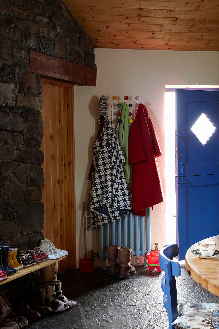 Coats hang above radiator in kitchen with exposed stone wall