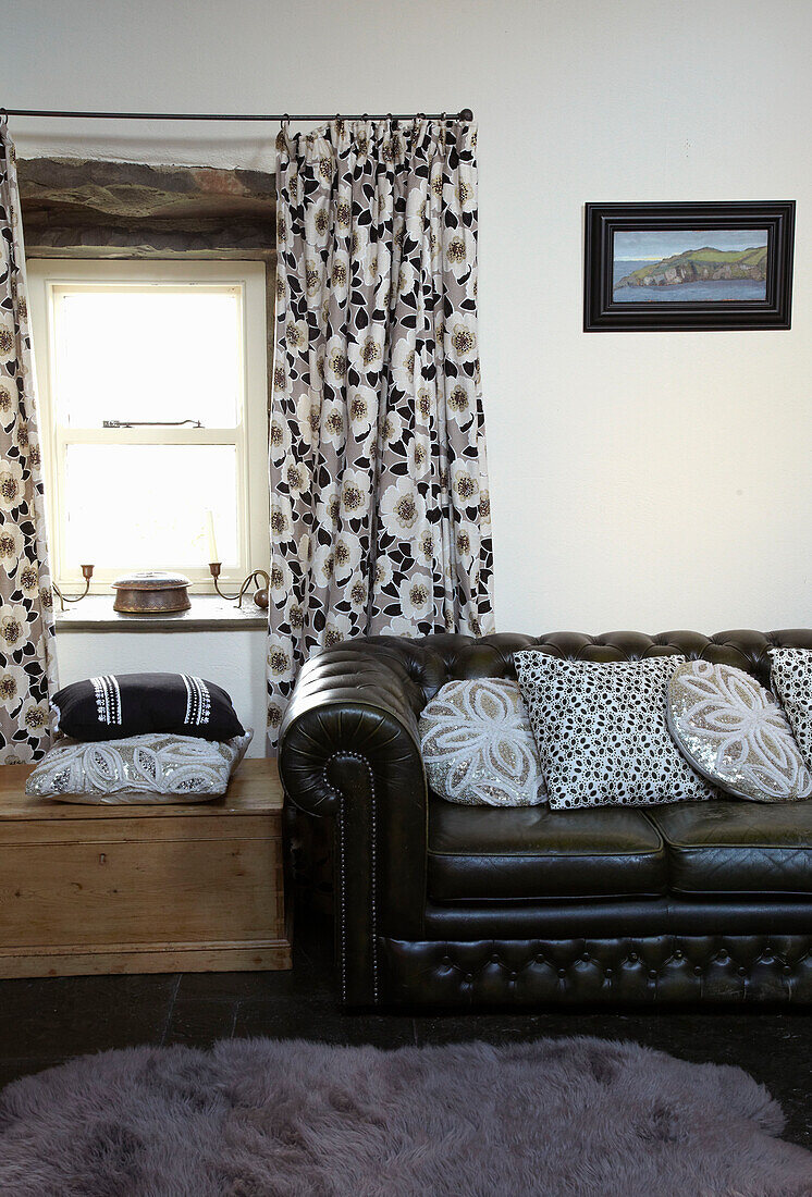Floral patterned curtains and black Chesterfield sofa