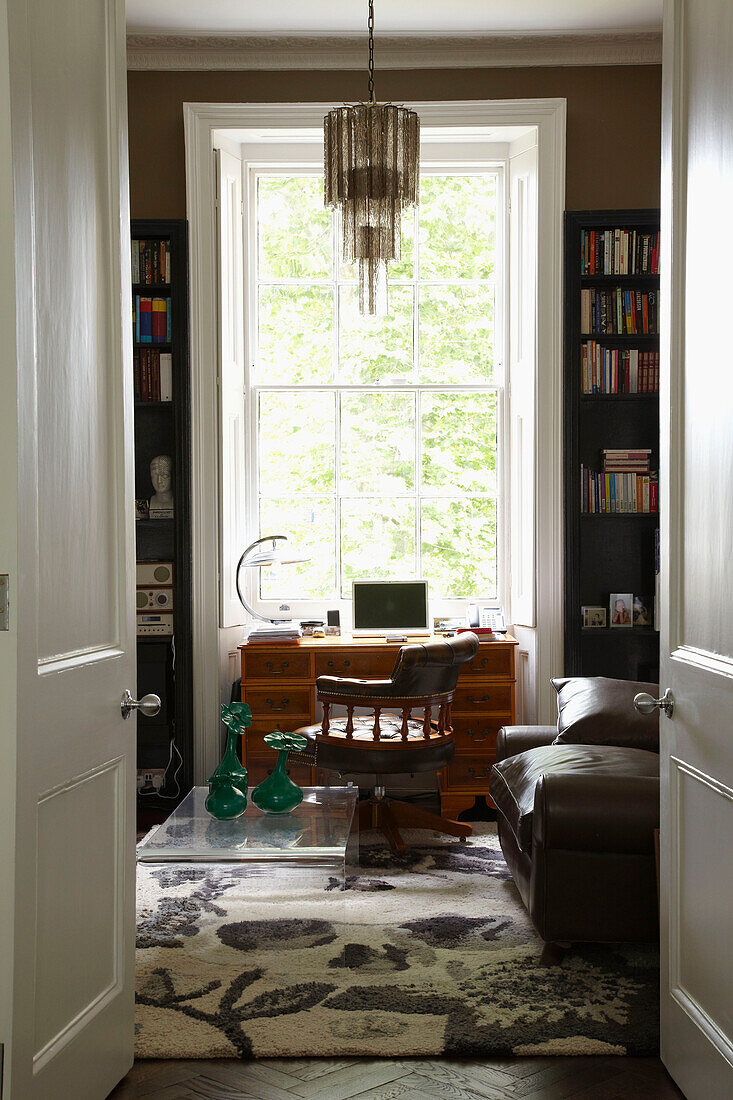 Holztisch zwischen Bücherregalen am Fenster einer Londoner Wohnung