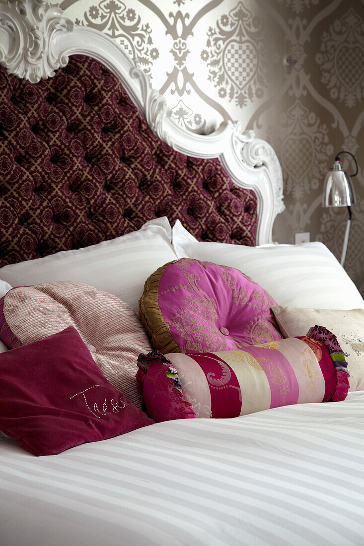 Verschiedene Kissen auf einem Doppelbett in der Wohnung eines Londoner Modedesigners