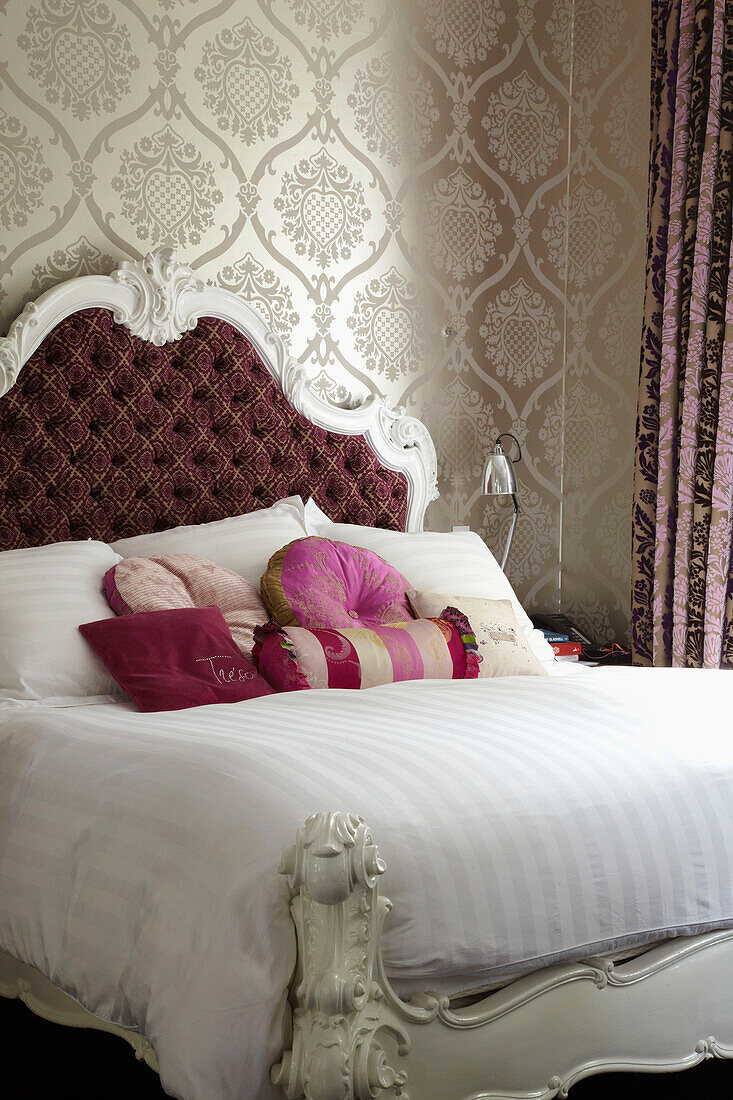 Verschiedene Kissen auf einem Doppelbett in der Wohnung eines Londoner Modedesigners