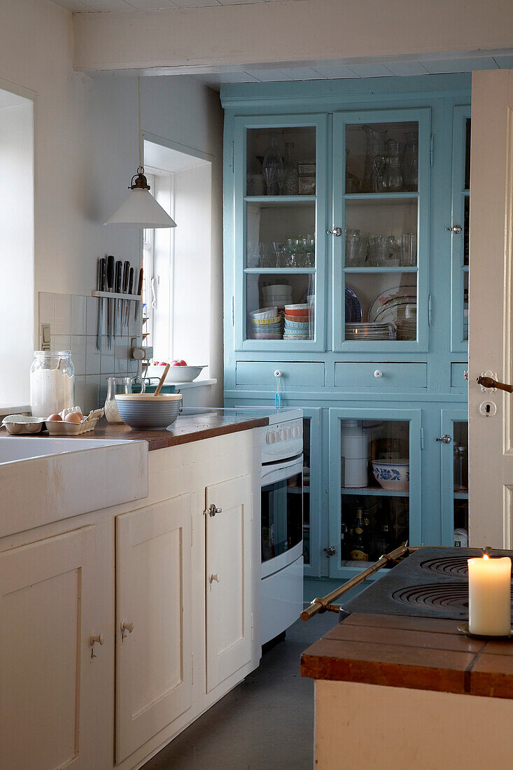 Bright blue dresser in rustic kitchen with burning candle