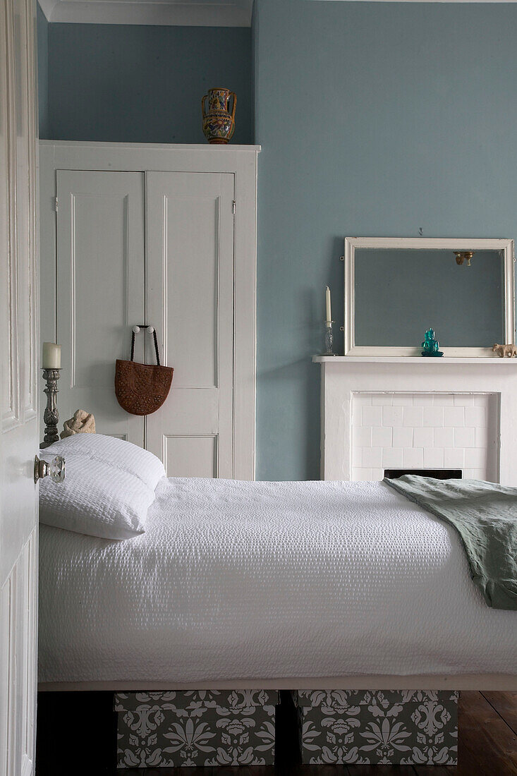 View through open door to double bed in front of fireplace in blue bedroom