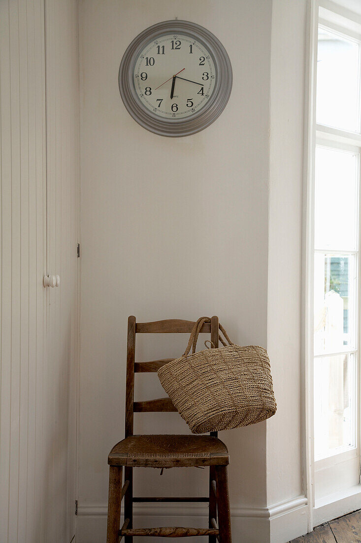 Clock above wooden chair with basket