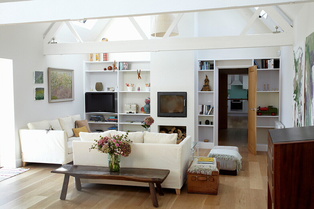 Weißes Wohnzimmer mit Balken und Fernseher auf einem Regal
