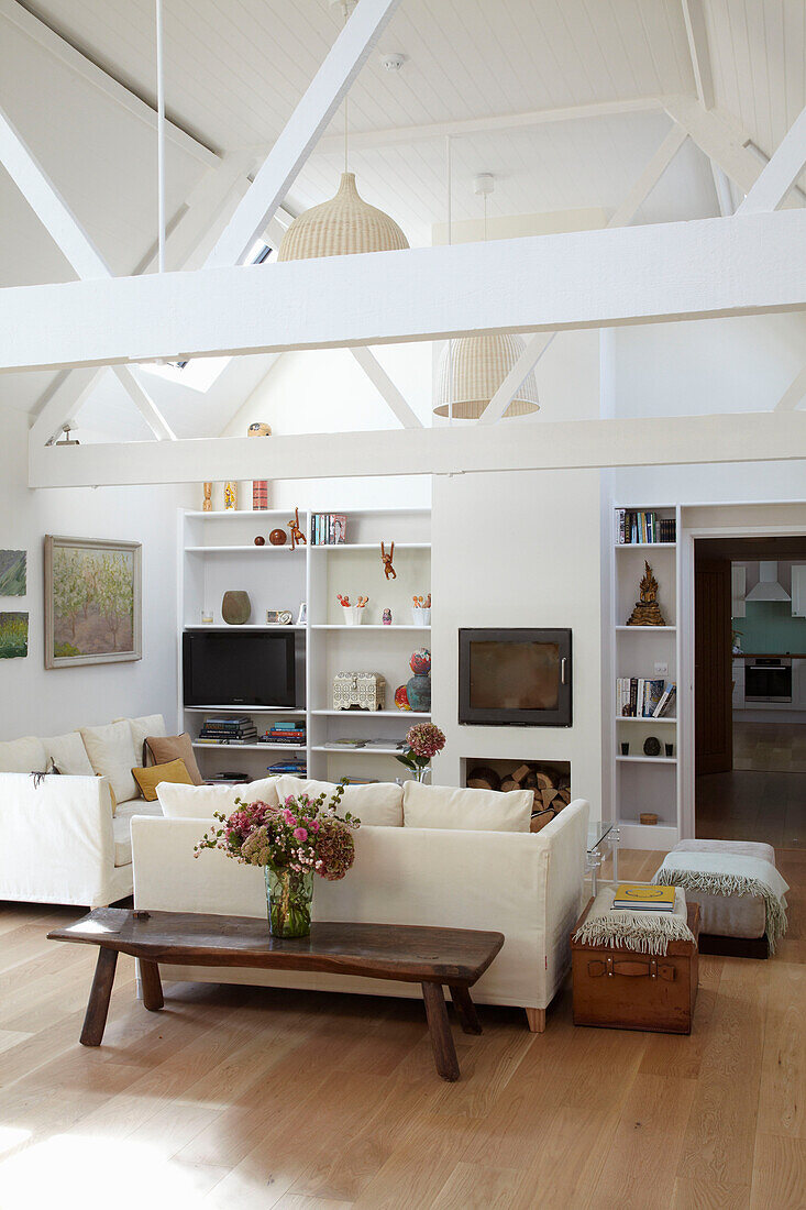 Weißes Wohnzimmer mit Balken und Fernseher auf einem Regal