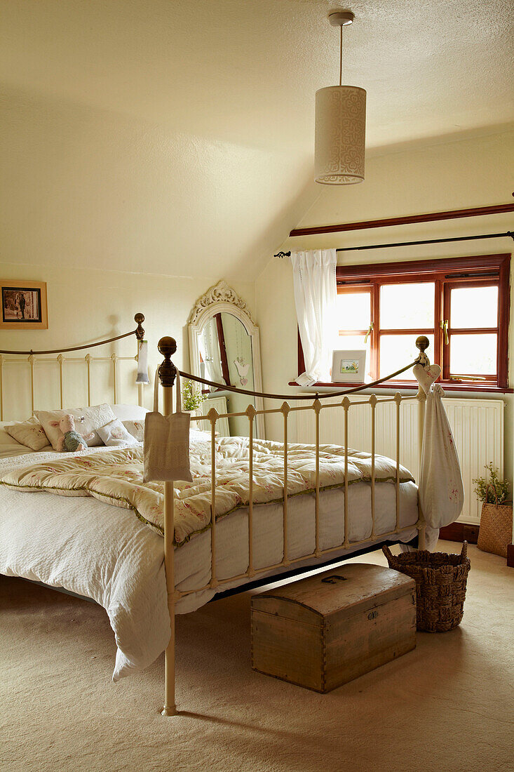 Double bed with quilt on wrought iron bed in West Sussex home, England, UK