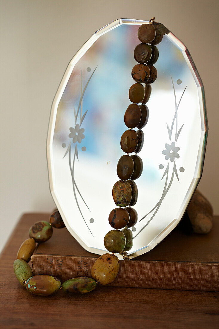 Beaded necklace and book with vintage mirror in Brighton townhouse, Sussex, England, UK