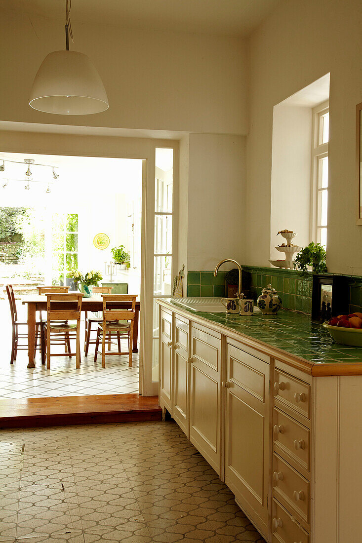 Blick durch die Schiebetür der grün gefliesten Küche zum Essbereich eines Stadthauses in Brighton, Sussex, England