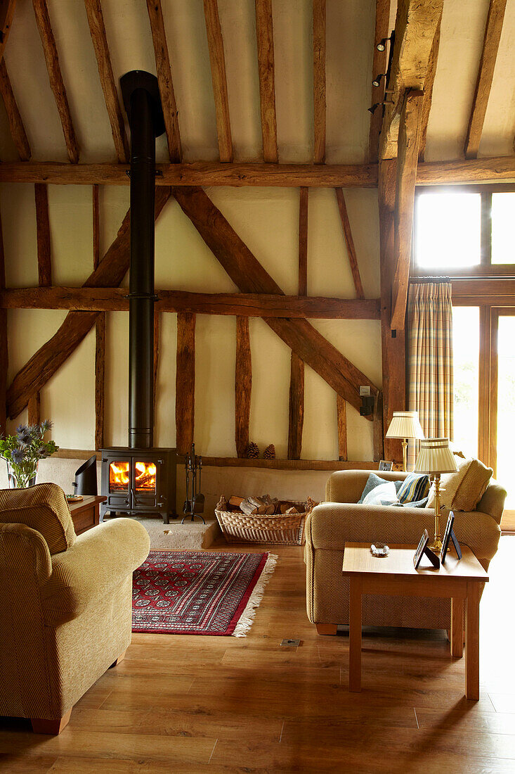 Beamed living room with wood burning stove in West Sussex home, England, UK