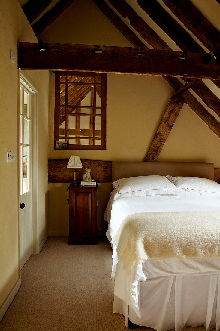 Doppelbett in einem Zimmer mit Holzbalkendecke in einem Haus in West Sussex, England, UK