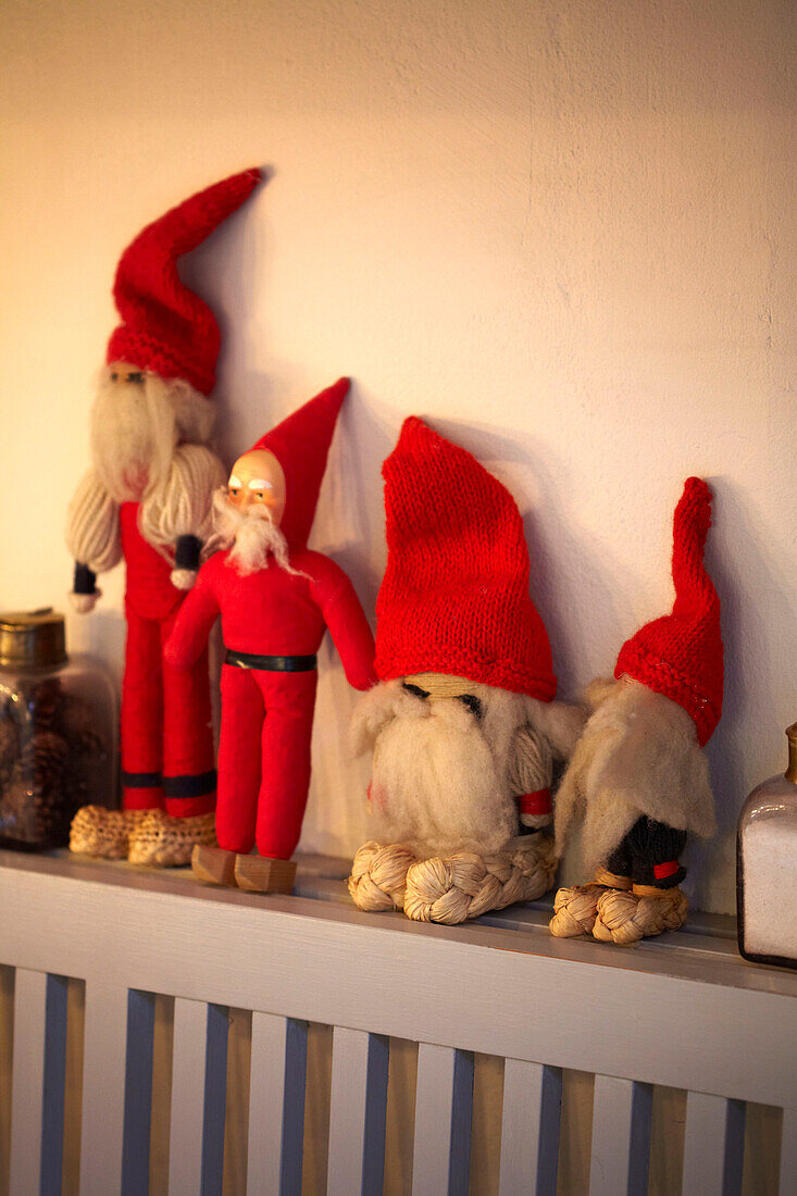 Four soft toys in Santa hats on radiator shelf