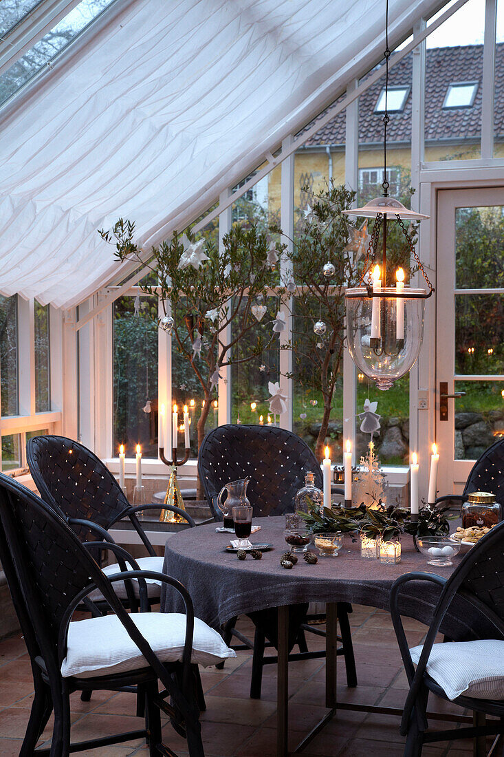 Lit candles on table with chairs in garden conservatory
