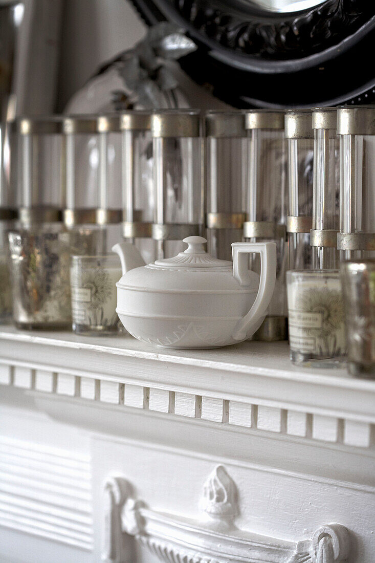 Glaswaren und Teekanne aus Keramik auf weißem Kaminsims