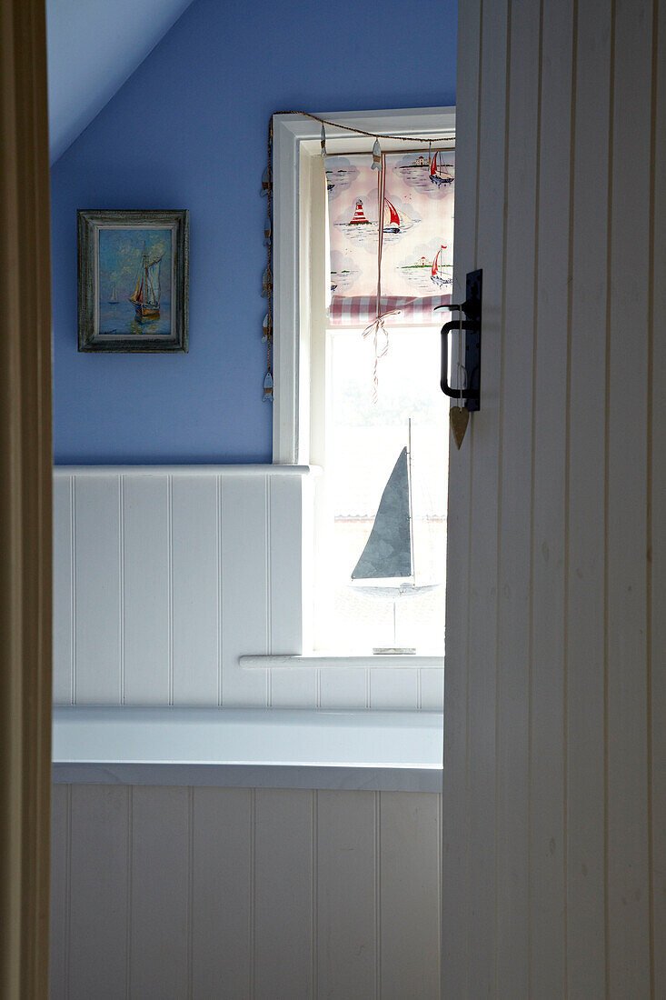 Blick durch die Tür in Badezimmer eines Strandhauses mit blau gestrichenen Wänden, Norfolk, UK