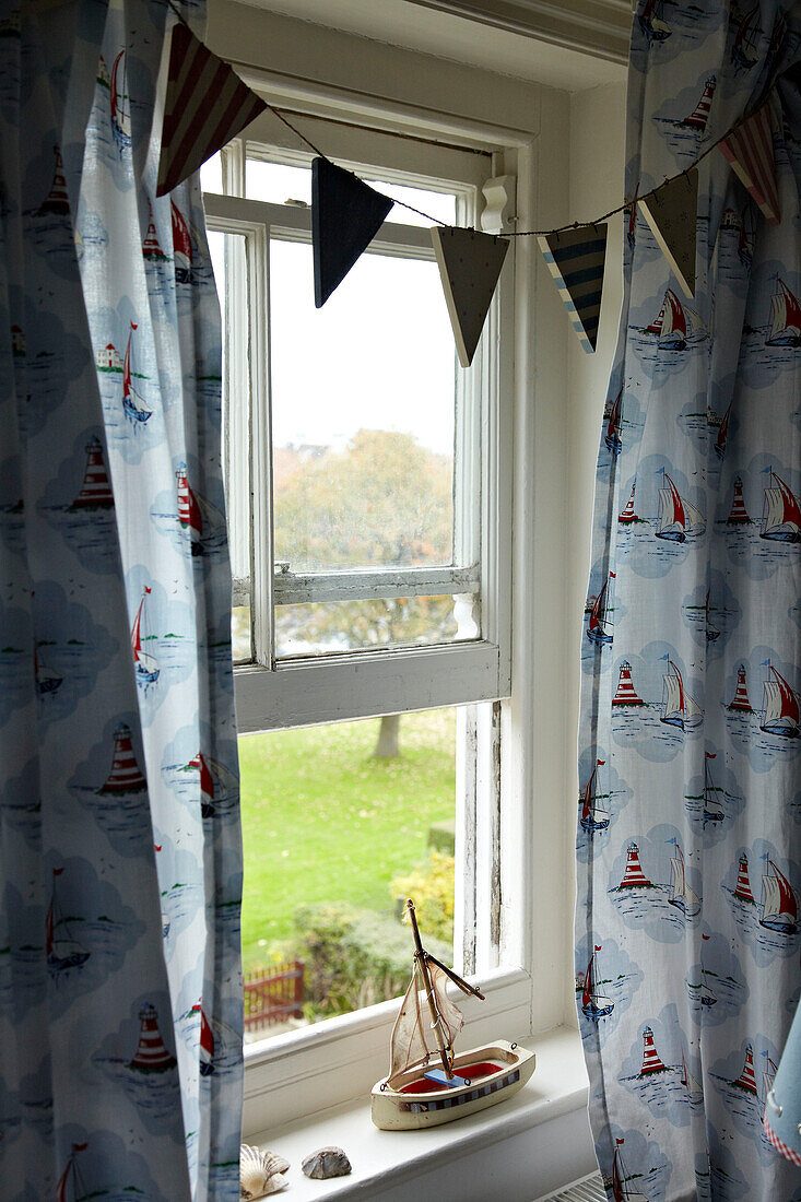 Spielzeugboot auf der Fensterbank im Schlafzimmer in einem Strandhaus in Norfolk, UK