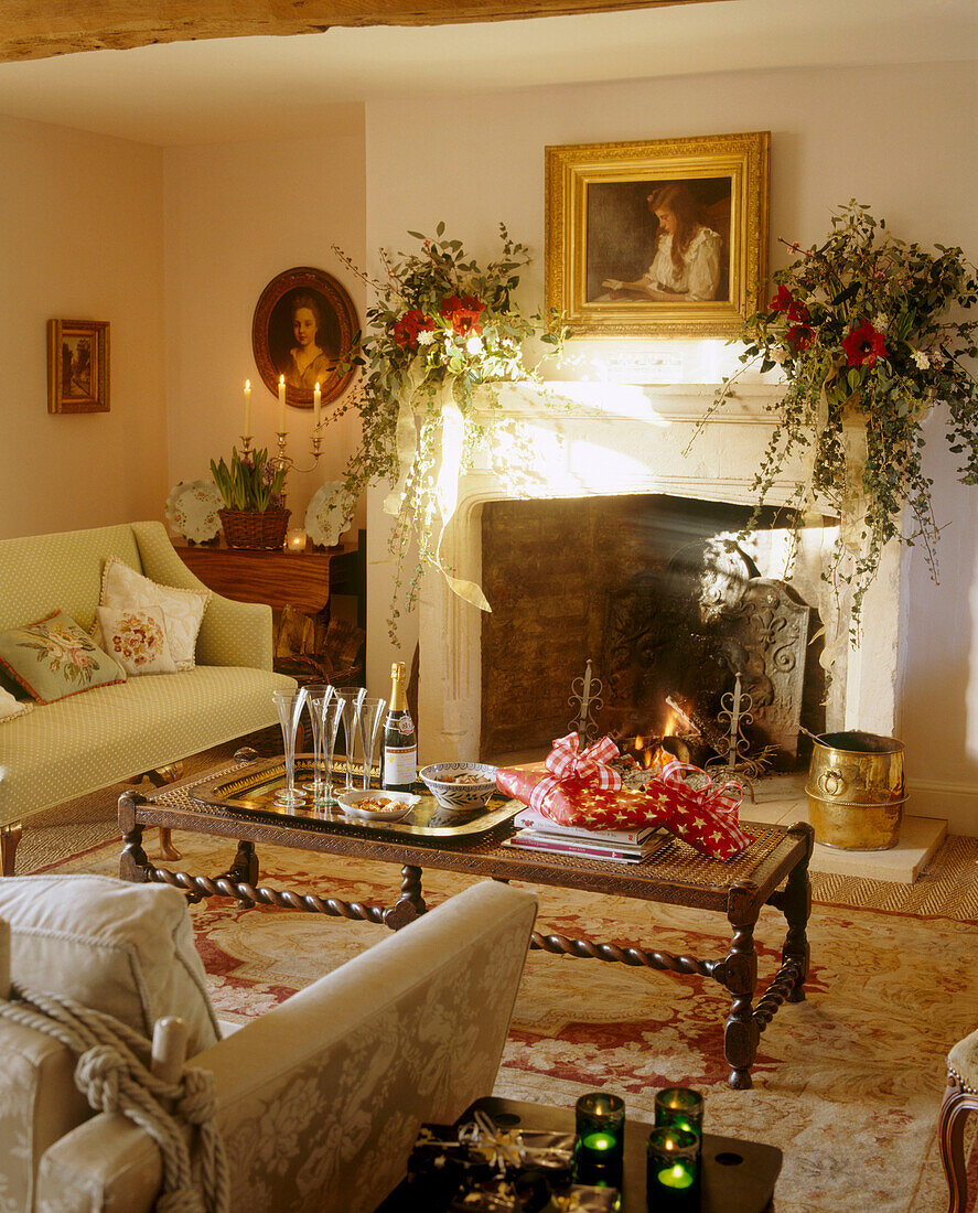 Ein traditionelles Wohnzimmer mit einem weihnachtlich geschmückten Steinkamin, gepolsterten Sofas und einem hölzernen Couchtisch, der von Kerzen und Blumenarrangements beleuchtet wird