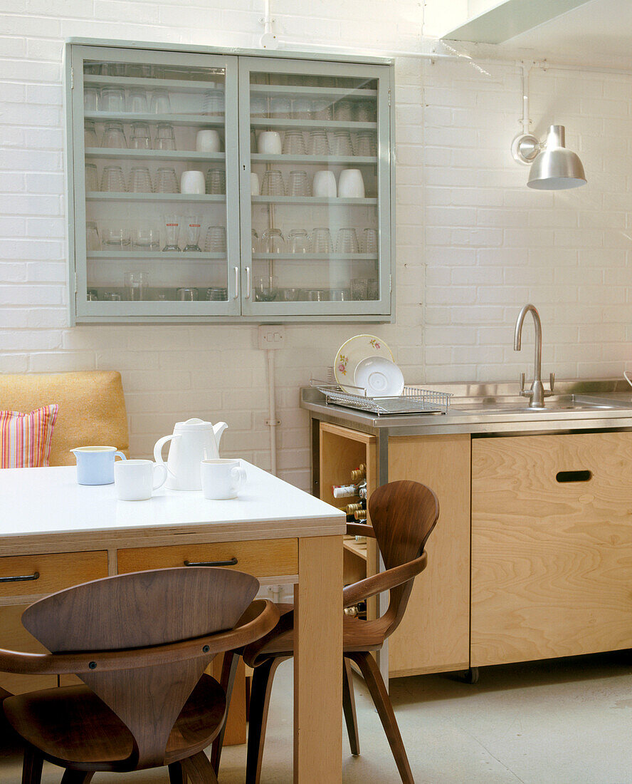 Ein moderner Küchentisch und eine Küchenarbeitsplatte mit einer Glasvitrine voller Gläser