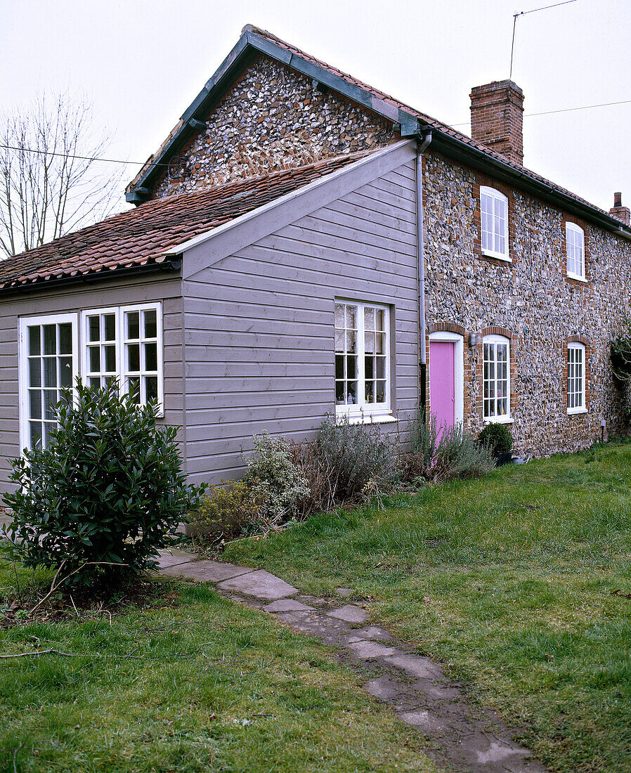 Exterior of flintstone cottage with weatherboard extension