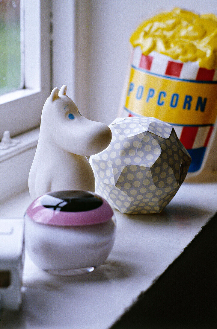 Objects on window sill including a moomin 60's glass paperweight