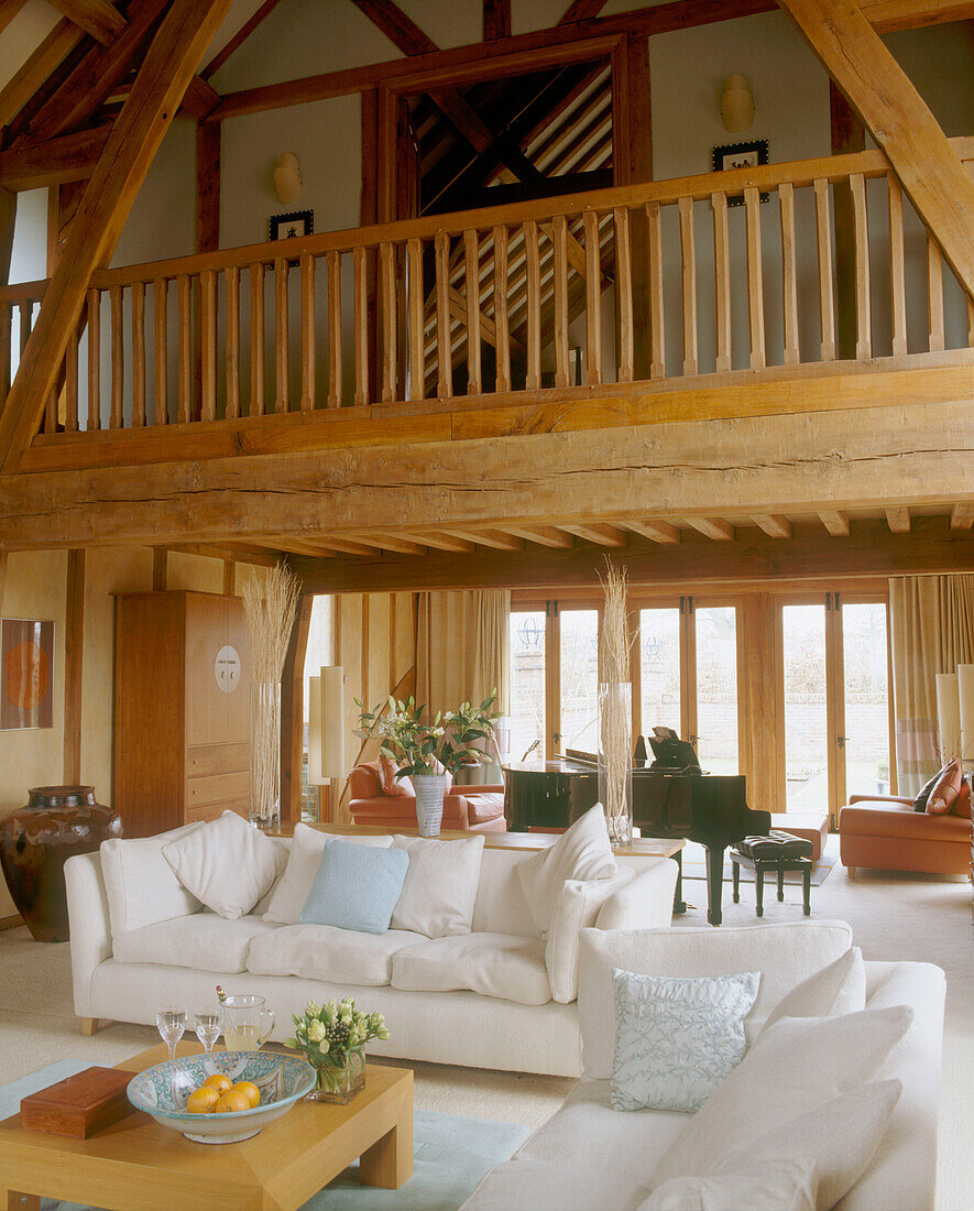 Blick in ein großes, umgebautes, offenes, traditionelles Wohnzimmer mit modernen Möbeln und einem Holzpodest