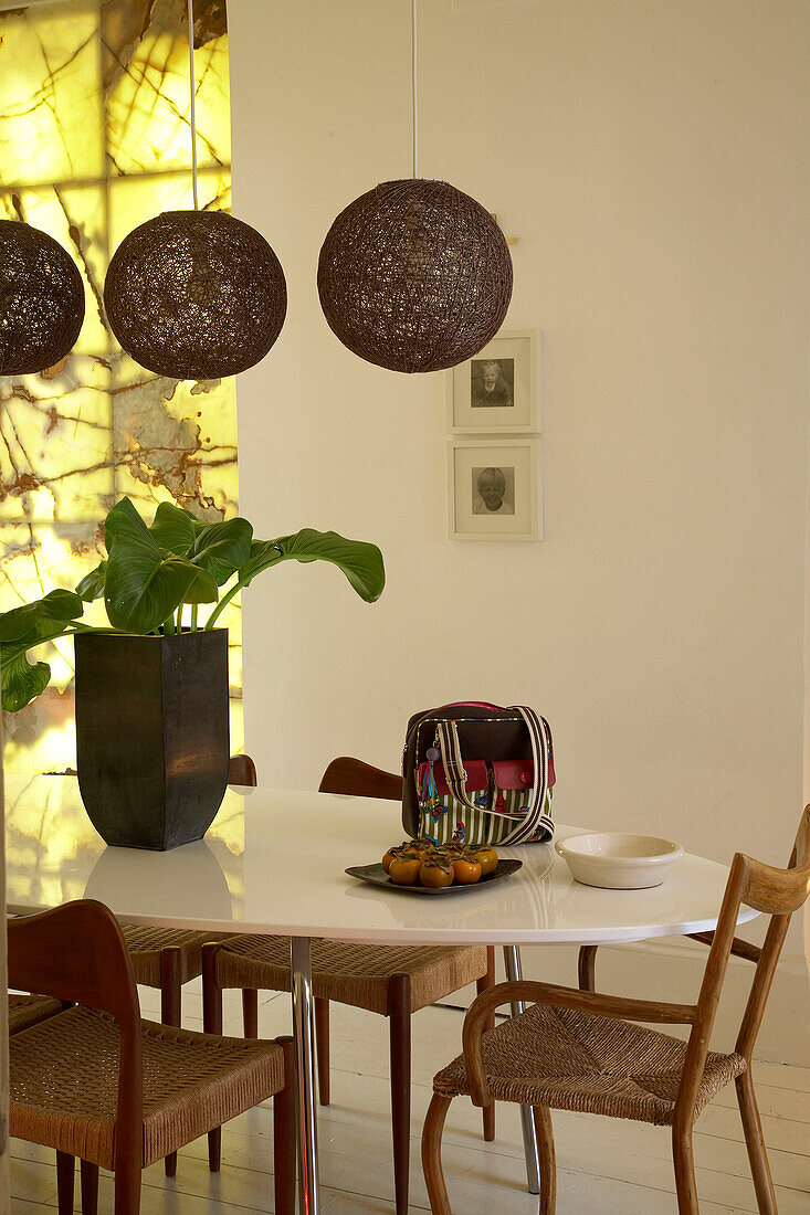 Ein modernes Esszimmer mit schwarzen Lampenschirmen über einem großen ovalen Esstisch, der von traditionellen Holzstühlen umgeben ist