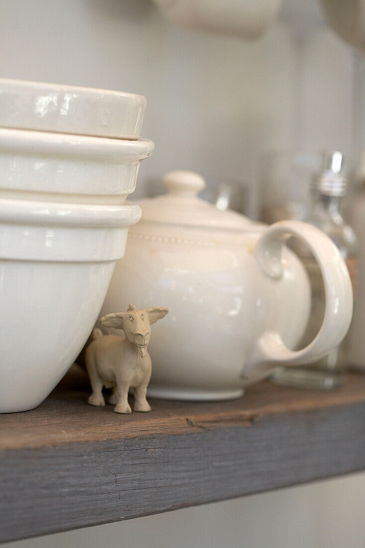 White tableware and model of goat on wooden shelf