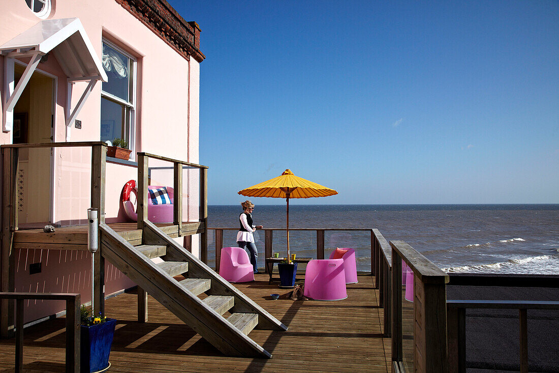 Woman on balcony terrace of Cromer beach house in Norfolk, UK