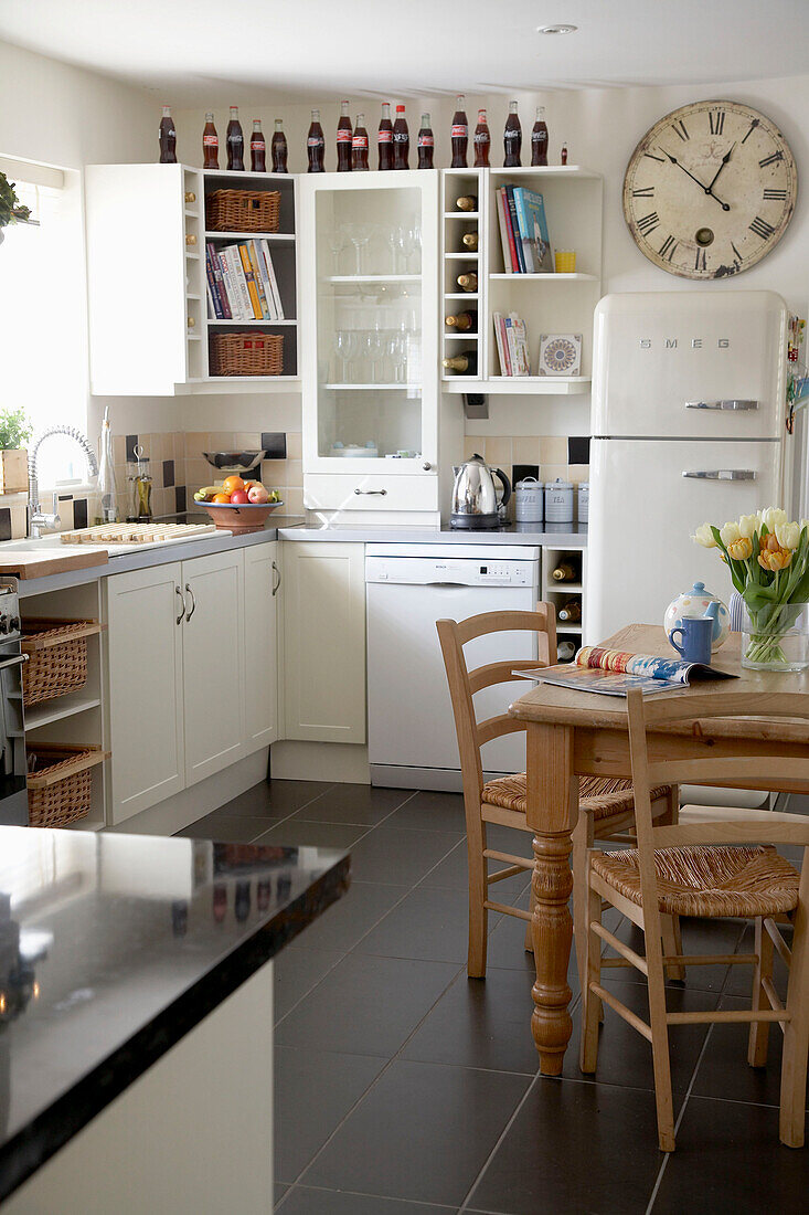 Eine moderne Küche im Landhausstil mit weißen Schränken und einem Frühstückstisch mit Stühlen aus Holz
