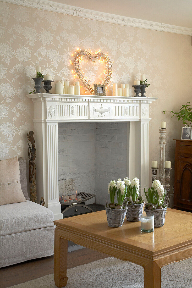 Kamin im Wohnzimmer im traditionellen Landhausstil mit herzförmiger Beleuchtung, niedrigem Holztisch und Blumen in Körben