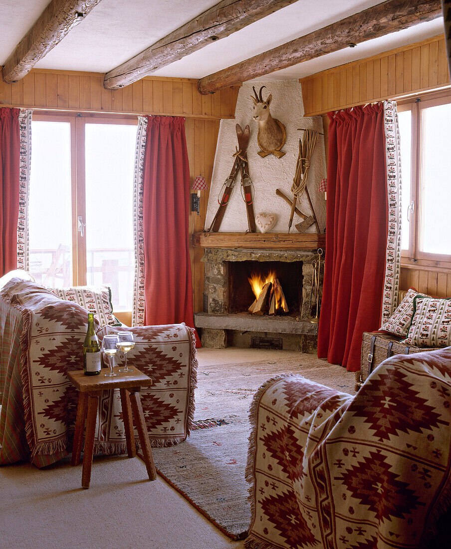 Wohnzimmer mit Steinkamin, Balkendecke und Sofas mit Überwürfen