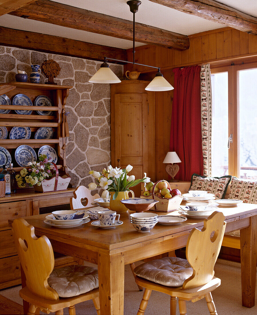 Esszimmer mit Balkendecke, Sichtmauerwerk, Tisch und Stühlen aus Kiefernholz