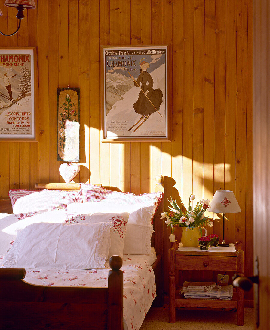 Schlafzimmer mit holzgetäfelten Wänden und Bett mit geblümter Bettwäsche