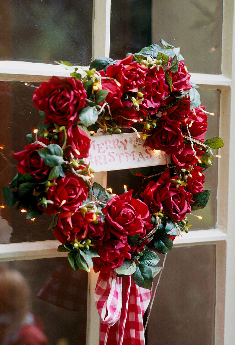 Weihnachtskranzes aus roten Rosen an einem Außenfenster