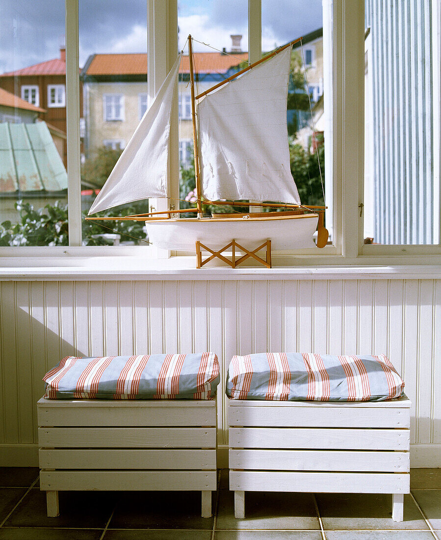 Holzsitze mit Streifenmuster-Kissen unter dem Fenster