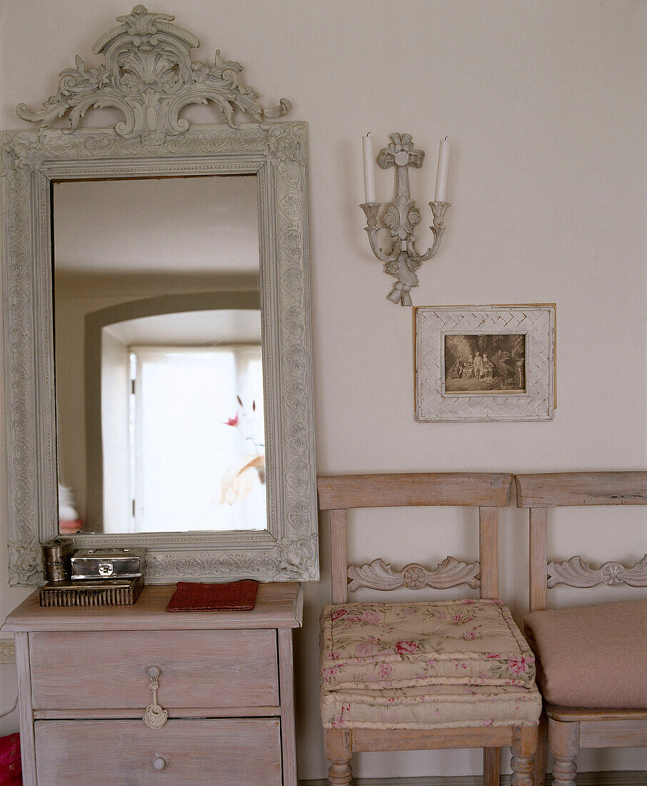 Wohnzimmer mit Stühlen und geschnitztem Spiegel auf Kommode
