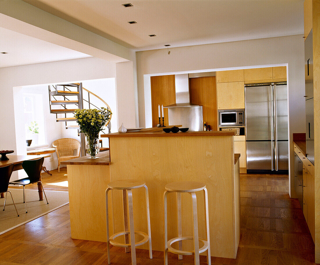 Moderner offener neutraler Küchen-Essbereich mit zentraler Holzinsel und Frühstücksbarhockern