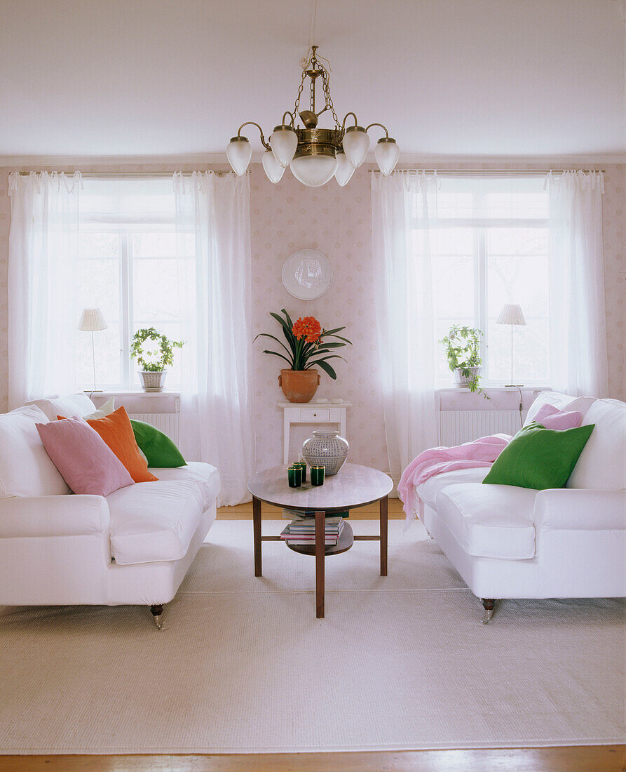 Ein Wohnzimmer im Landhausstil mit zwei weißen Sofas und Couchtisch dazwischen