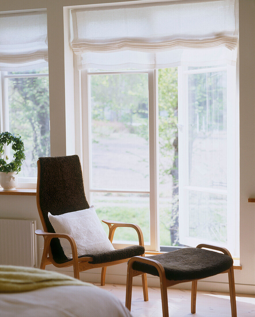 Detail eines modernen Schlafzimmers mit Sessel und Fußhocker