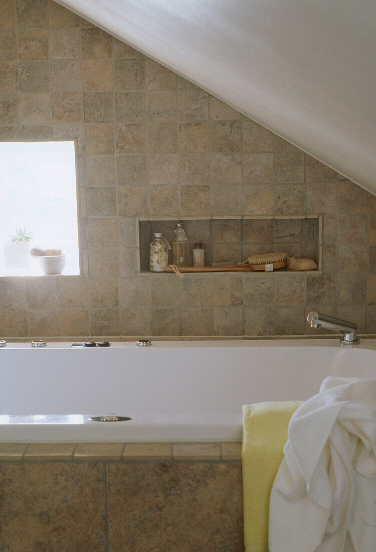 Detail eines modernen Badezimmers mit einer Badewanne, gefliesten Wänden und schräger Decke