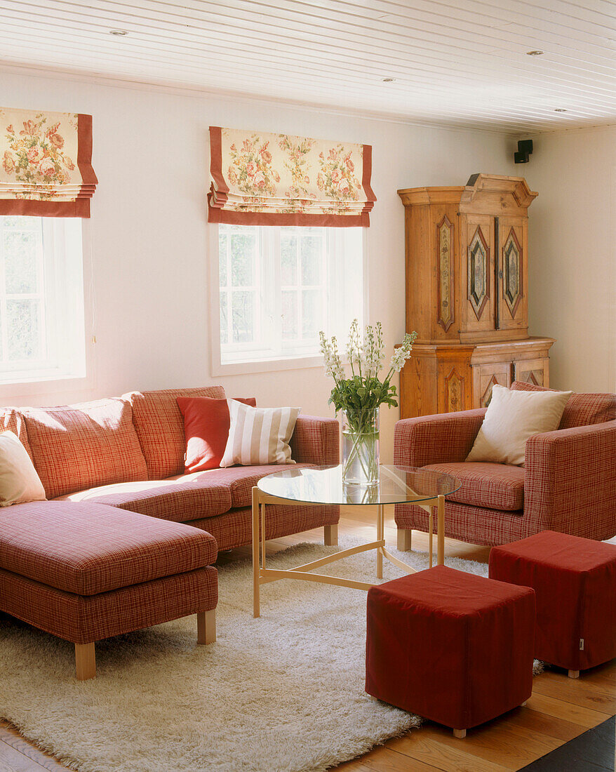Wohnzimmer mit roten Möbeln um einen runden Couchtisch aus Glas